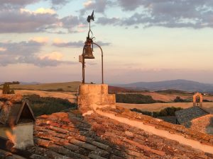 Clay tile rooftop with bell tower and weather vane overlooking the Borgo Pignano estate (Volterra, Province of Pisa, Italy).